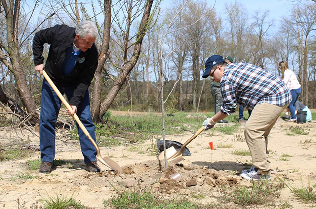 DNREC Secretary Shawn M. Garvin works with a colleague to plant another tree in the Tree for Every Delawarean Initiative.