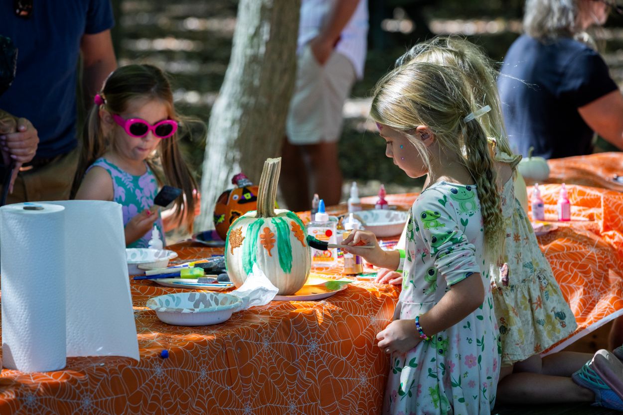 Children enjoying an outdoor festival decorating pumpkins.