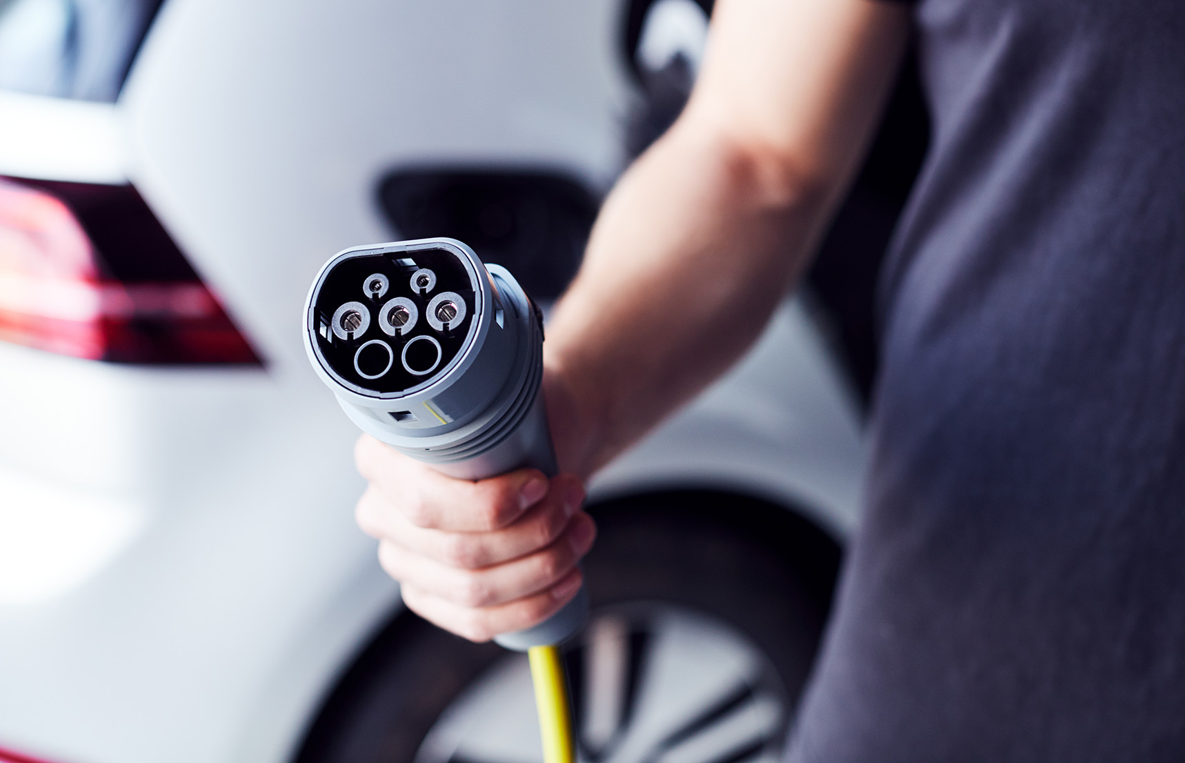 Photo of a person with electric vehicle holding an EV charging plug