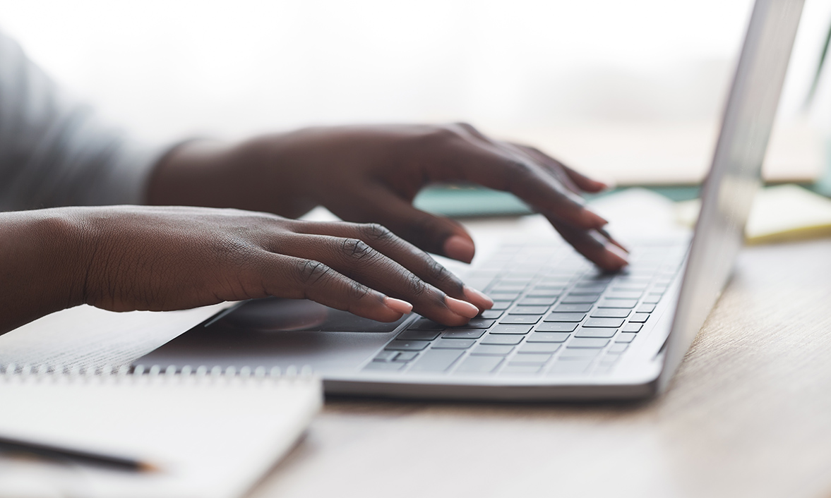 A picture of woman's handing typing on a computer to with a picture of charts and graphs