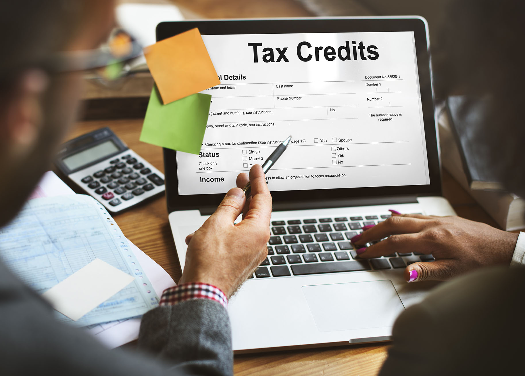 A picture of a man and woman's hands typing on a computer to with a picture an application for tax credits