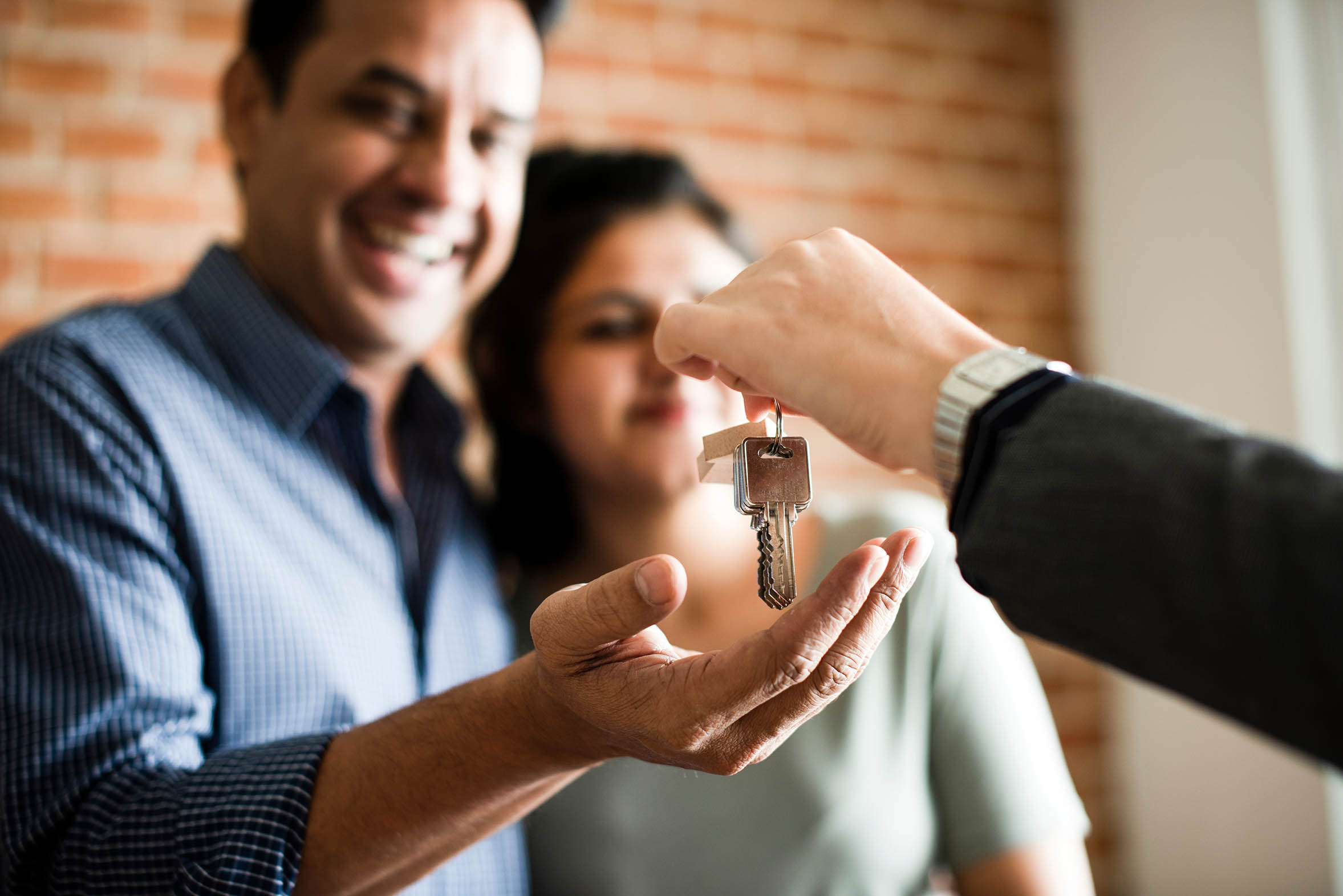 A picture of a smiling man and woman recieving keys from another person