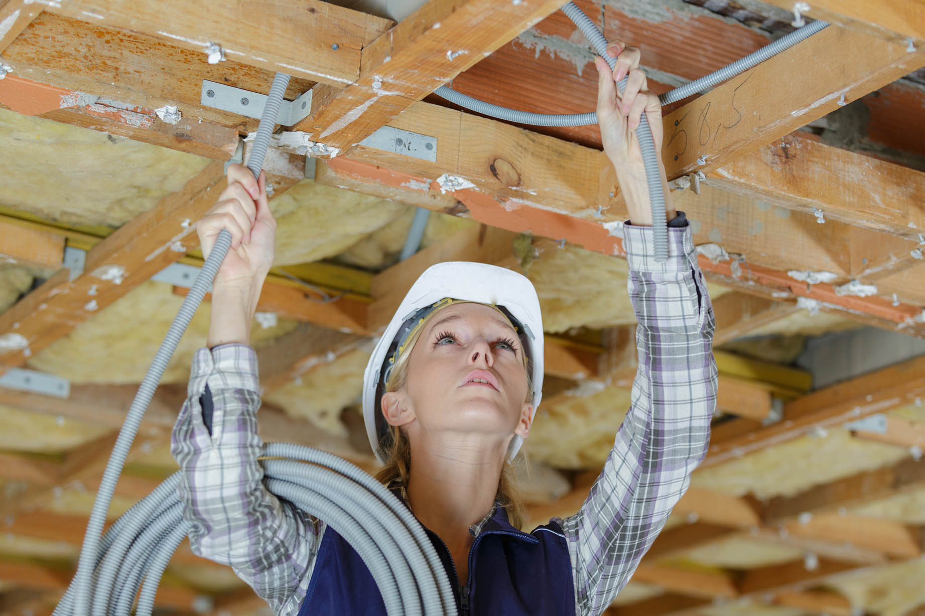 A picture of a woman installing cabling in a basement